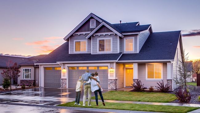 A family is standing in front of a large house.