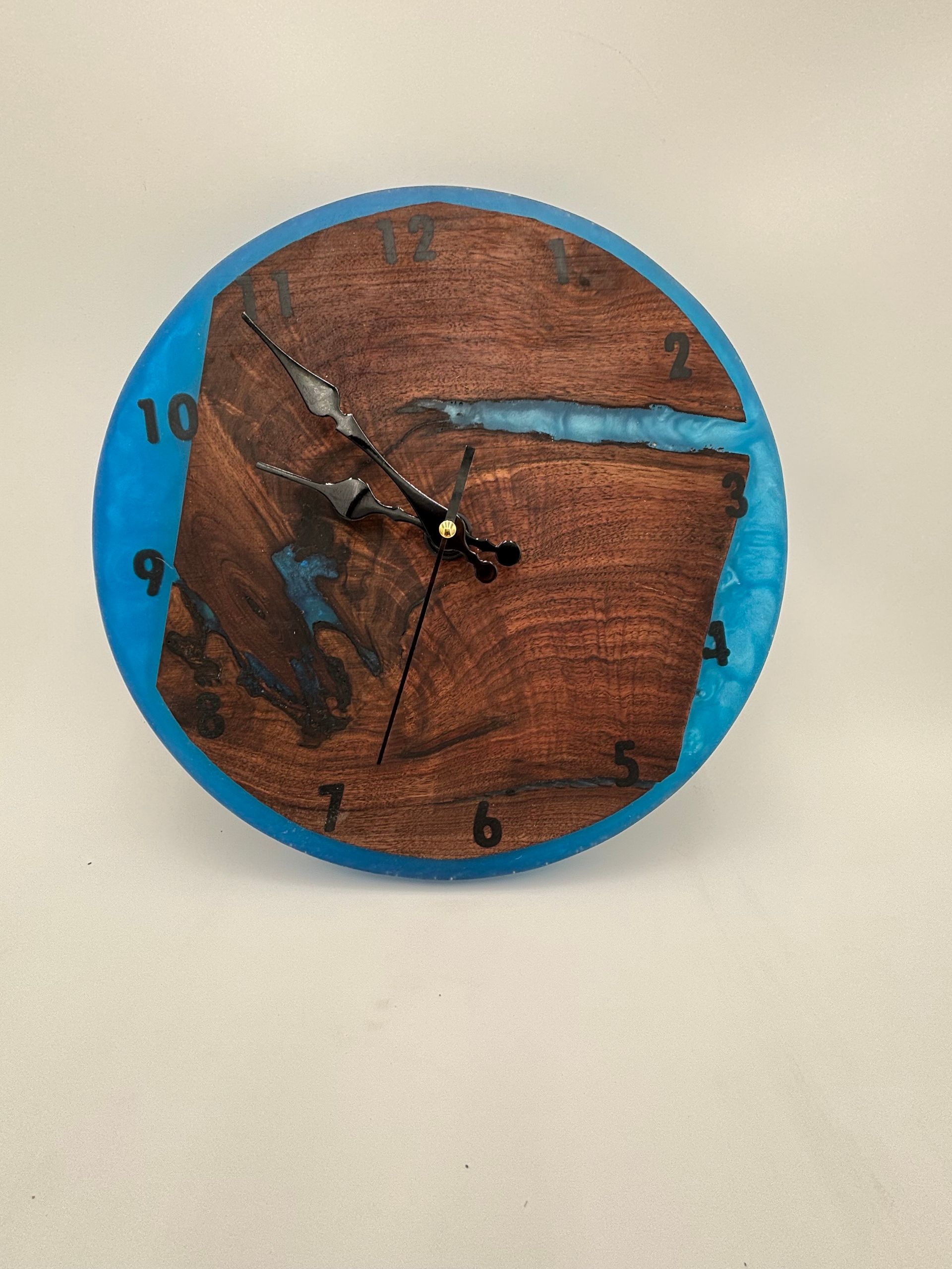 Clock made of wood and blue resin, black clock hands and numbers.