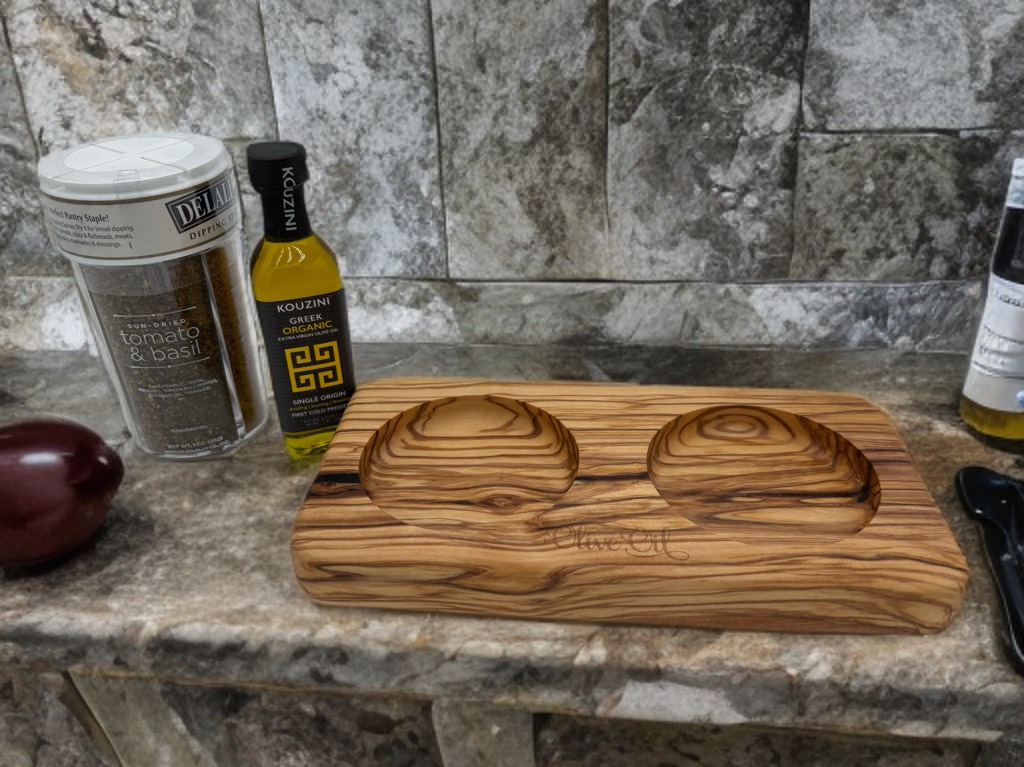 Olive oil bottles and a wooden serving board with dipping wells on a stone countertop.