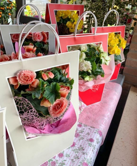 Sacchetti regalo rosa e bianchi pieni di mazzi di fiori su un tavolo decorato.