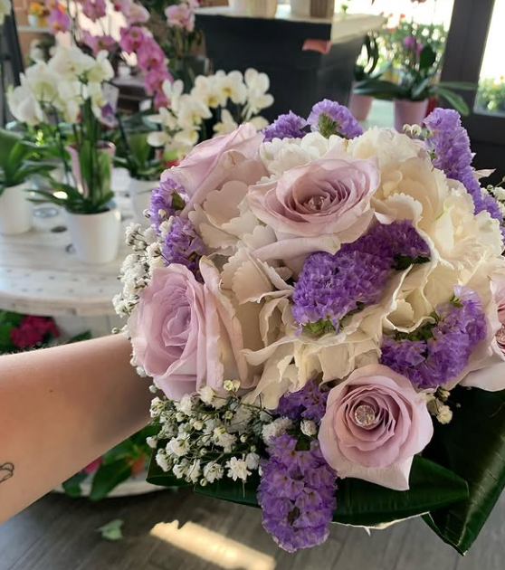 Bouquet di lavanda e rose bianche con accenti viola, tenuto in mano da una persona.