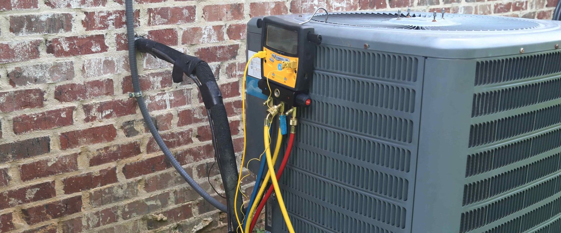 An air conditioner is being installed on a brick wall.