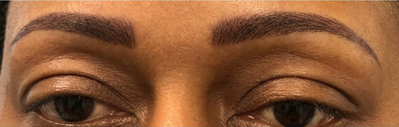 Close-up of a person's eyes and eyebrows with neatly groomed brows and neutral expression
