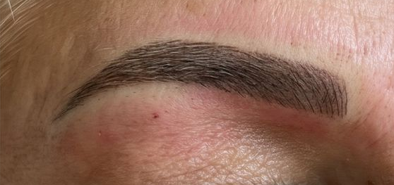 Close-up of a shaped dark eyebrow with a reddish tint above the eye