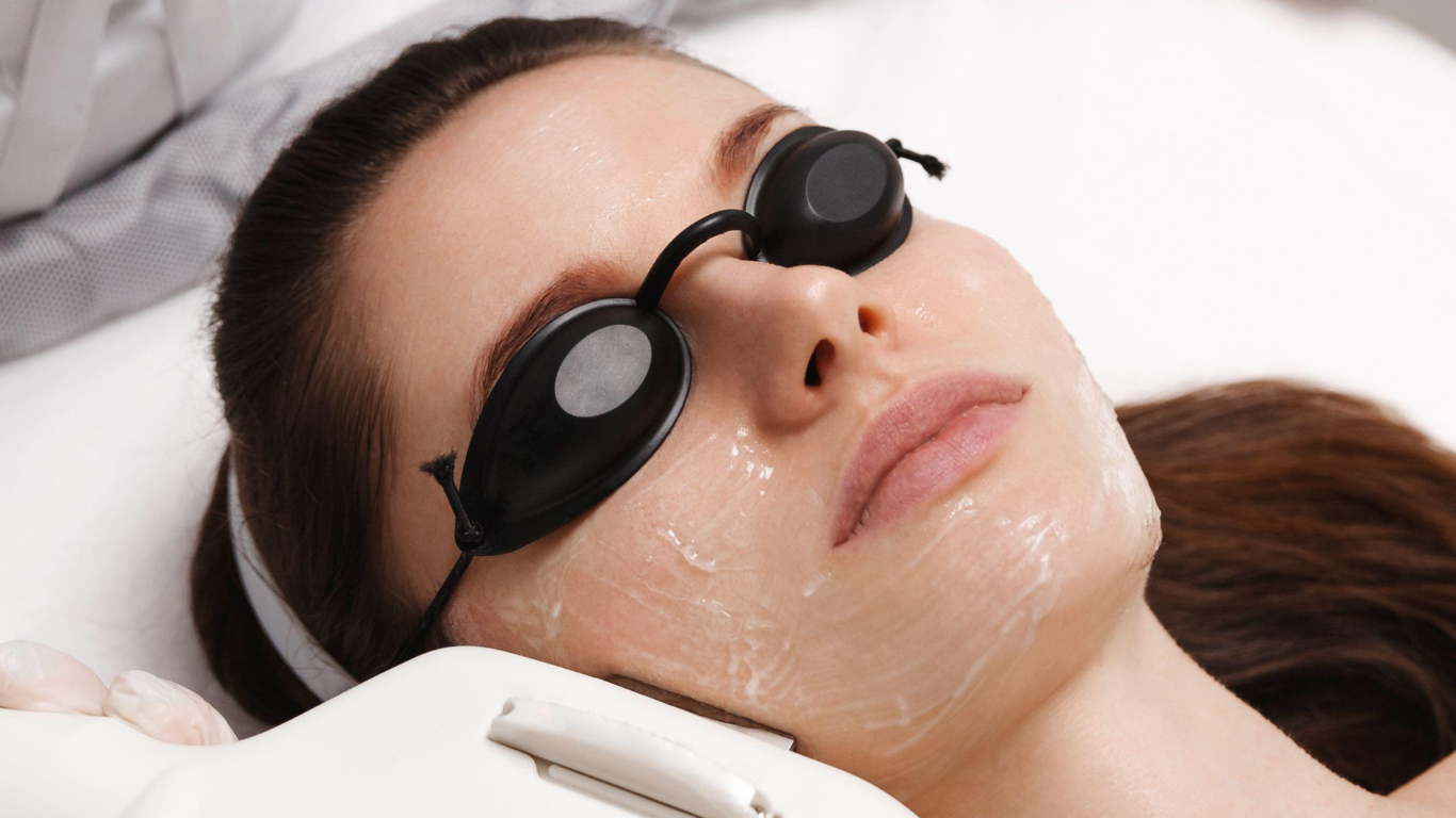 Person wearing black eye masks receiving a facial treatment while lying down