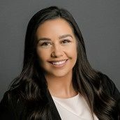 A woman in a white shirt and black jacket is smiling for the camera.