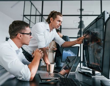 Two men are looking at a computer screen in an office.