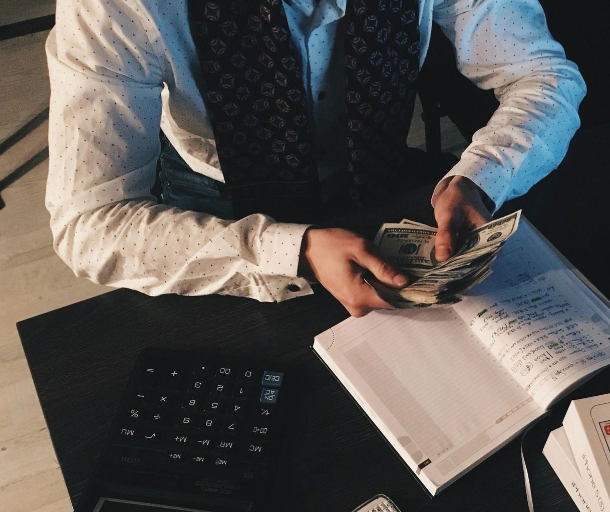 A man is sitting at a desk counting money