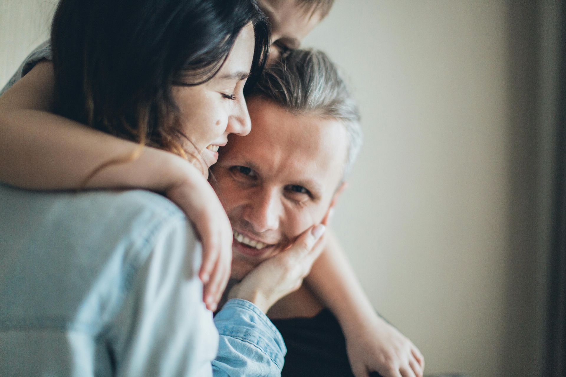 A woman is hugging a man and a child.