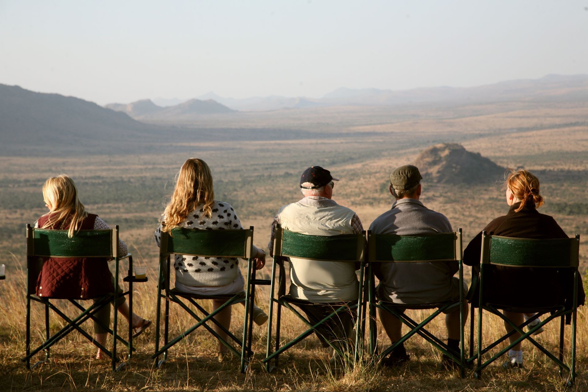 Five people sit in folding chairs overlooking the Lolldaiga Conservancy
