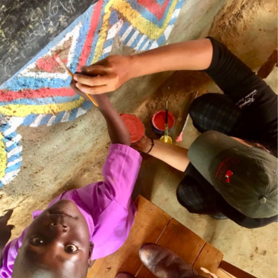 Two children painting a colorful mural on a wall, seen from above