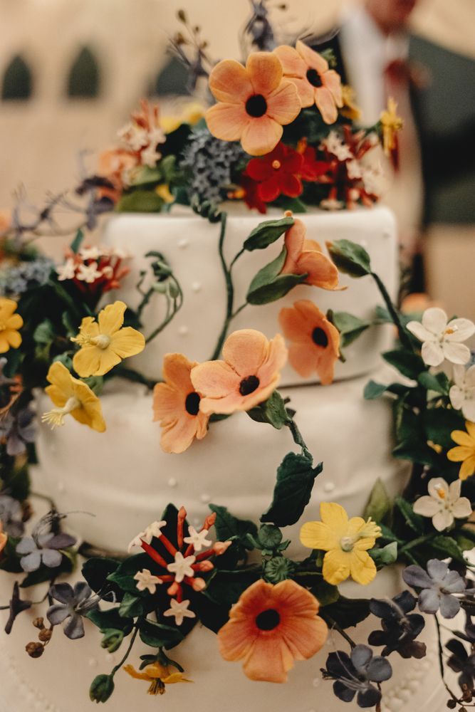 White tiered cake covered with colorful flowers and vines