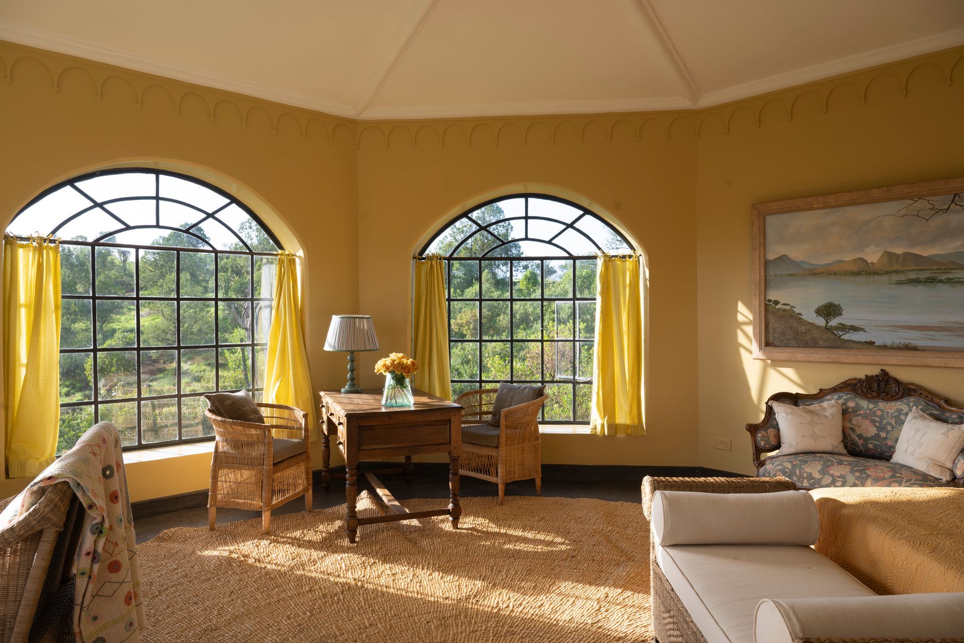 Sunlit yellow bedroom with arched windows, desk, bed, and coastal wall art
