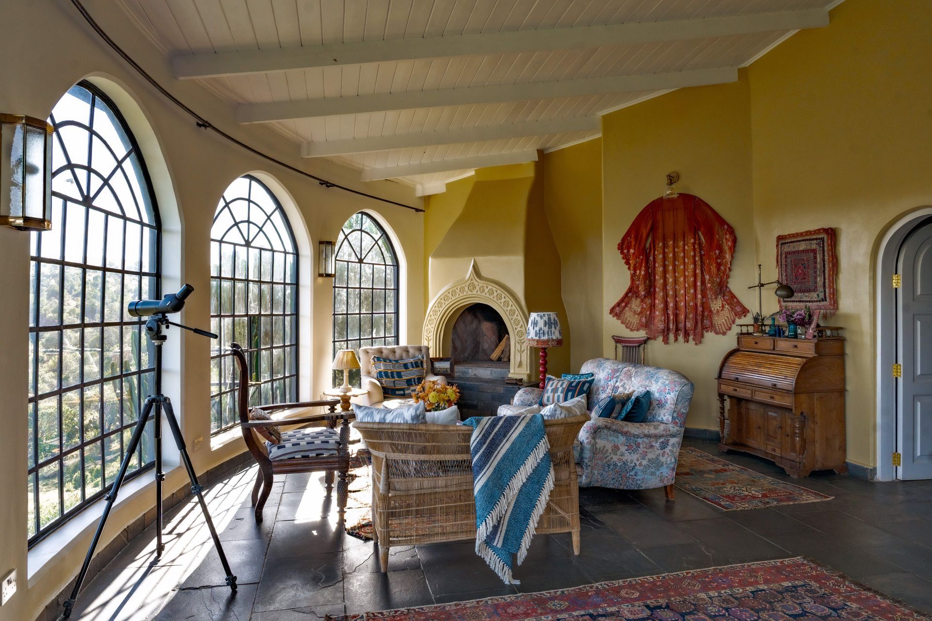 Bright sitting room with arched windows, wicker chairs, fireplace, and patterned rugs
