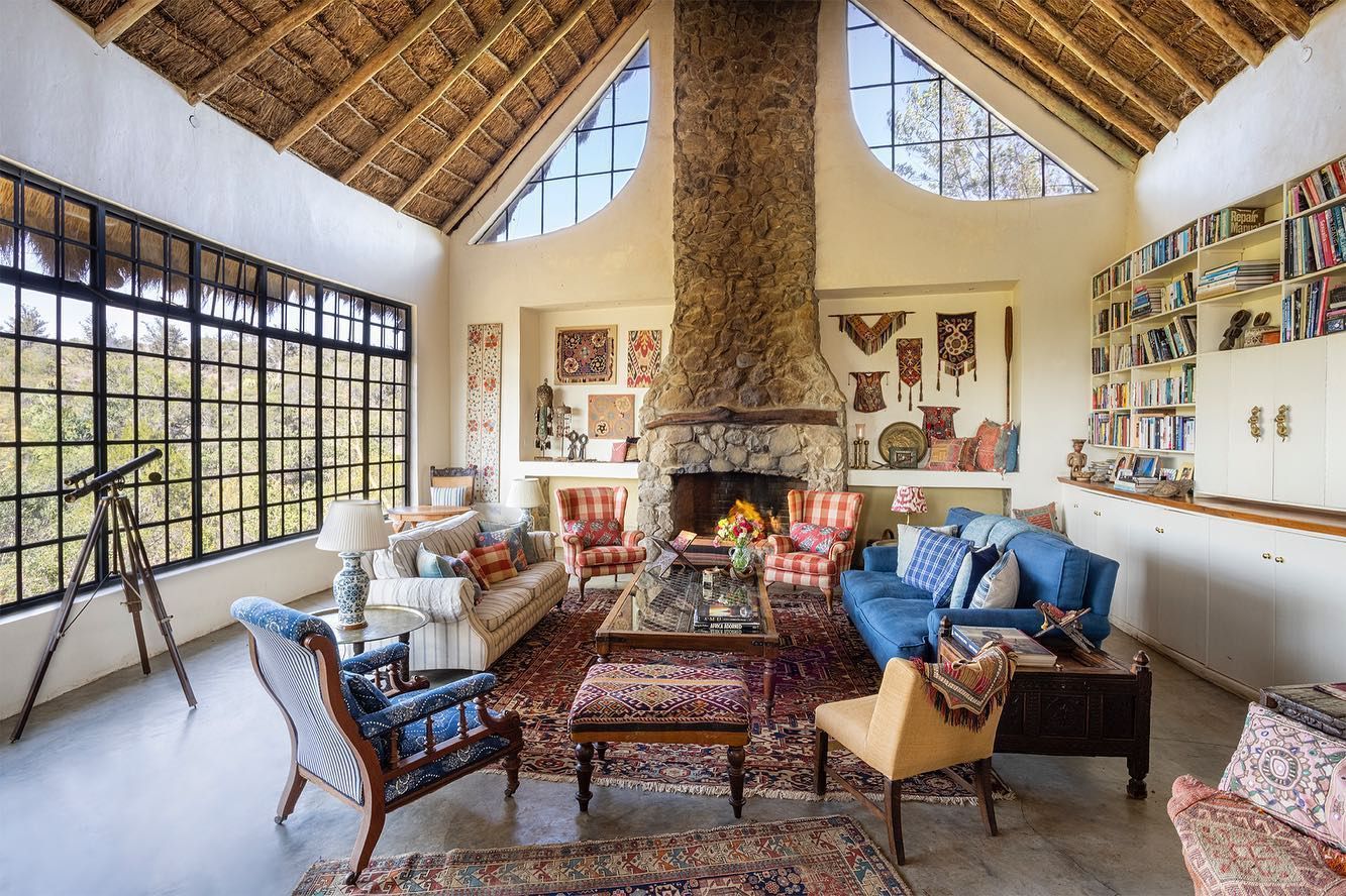 Cozy living room with vaulted wood ceiling, stone fireplace, colorful wall art, and blue sofa seating area