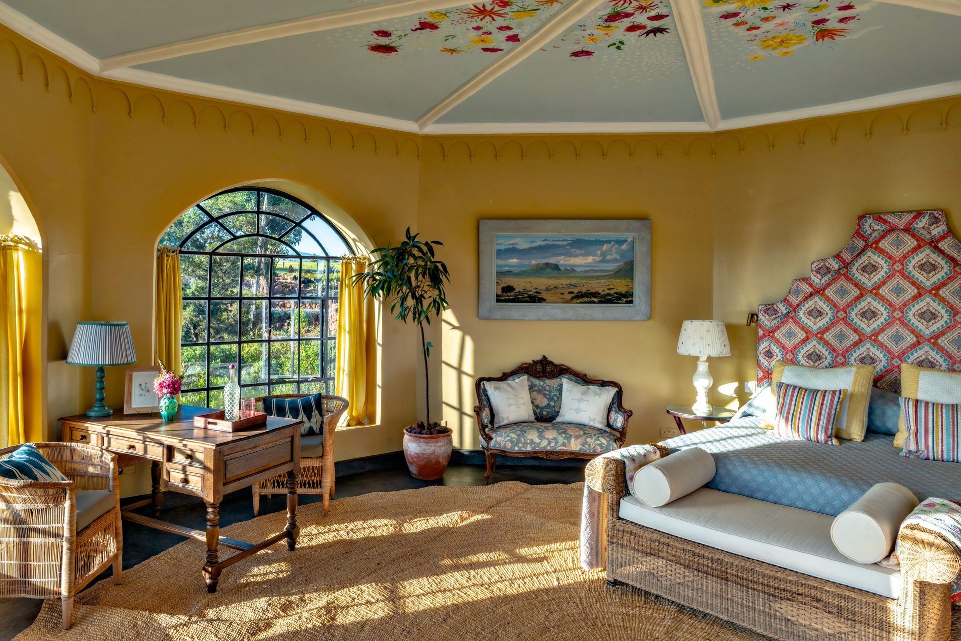Bright living room with arched window, yellow walls, patterned ceiling, and white sofa under a painting.