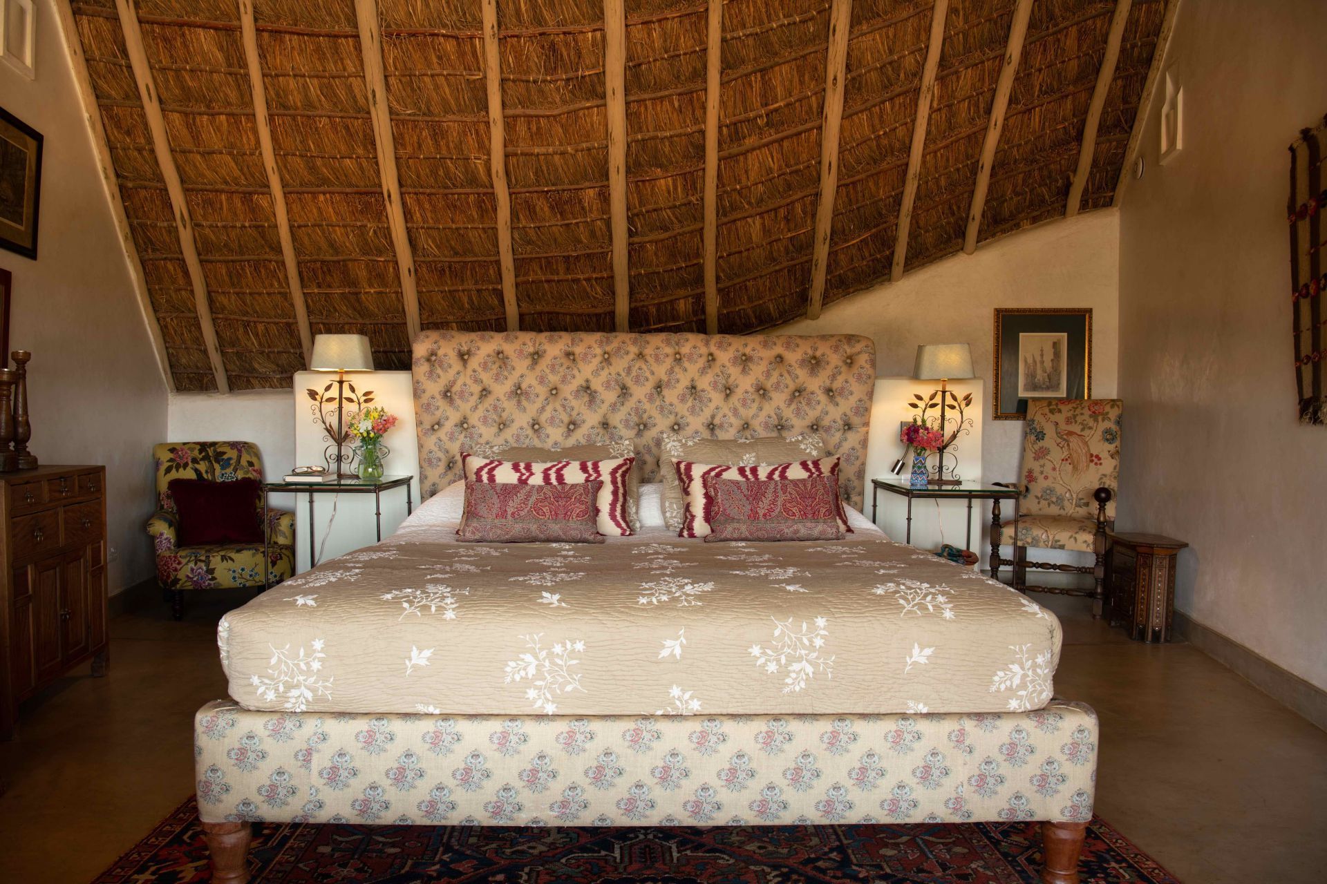 Rustic bedroom with a large bed, patterned pillows, and bedside lamps under a wood-beamed ceiling