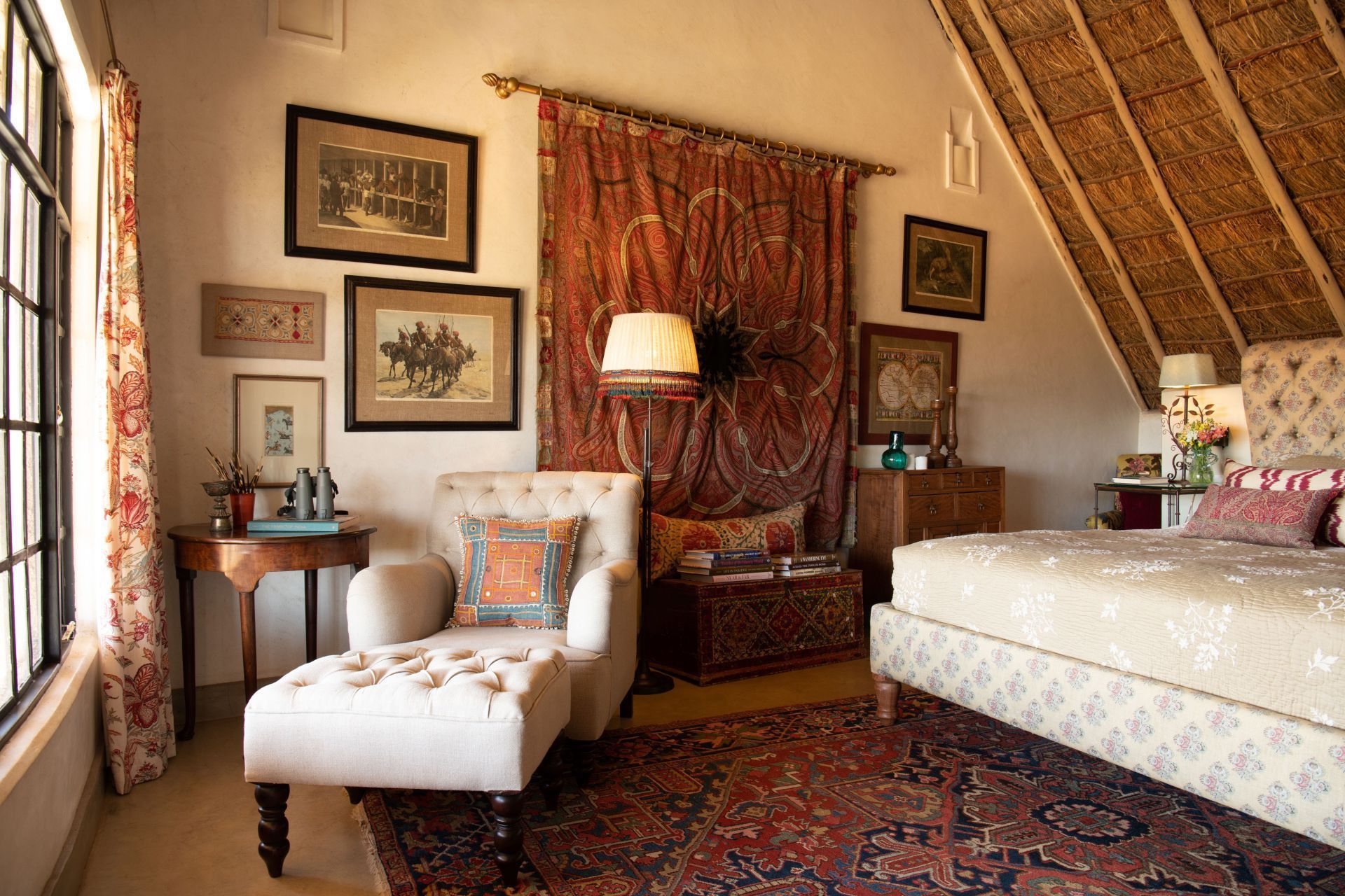 Cozy bedroom with twin beds, patterned rugs, warm lamps, and draped curtains in a sloped-ceiling room