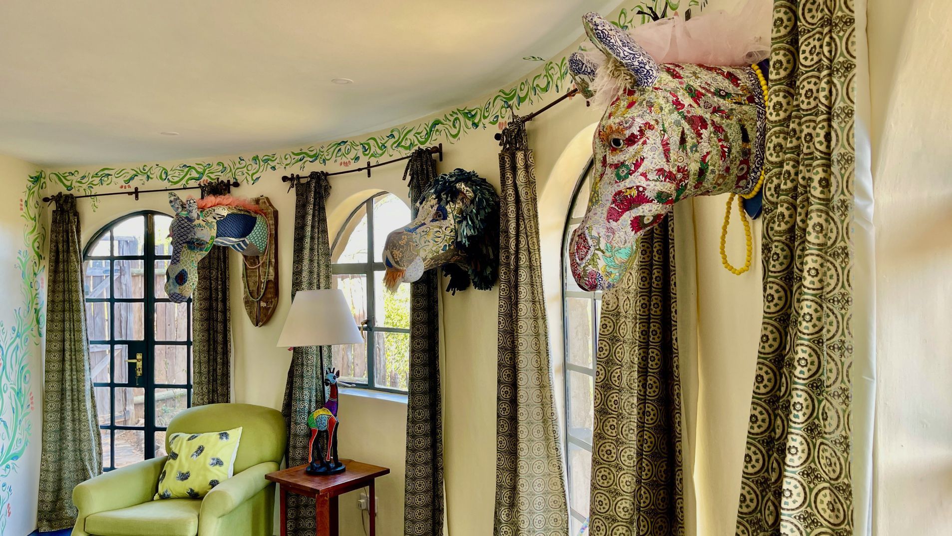 Living room with patterned curtains, arched windows, and decorative horse heads above chairs and side table