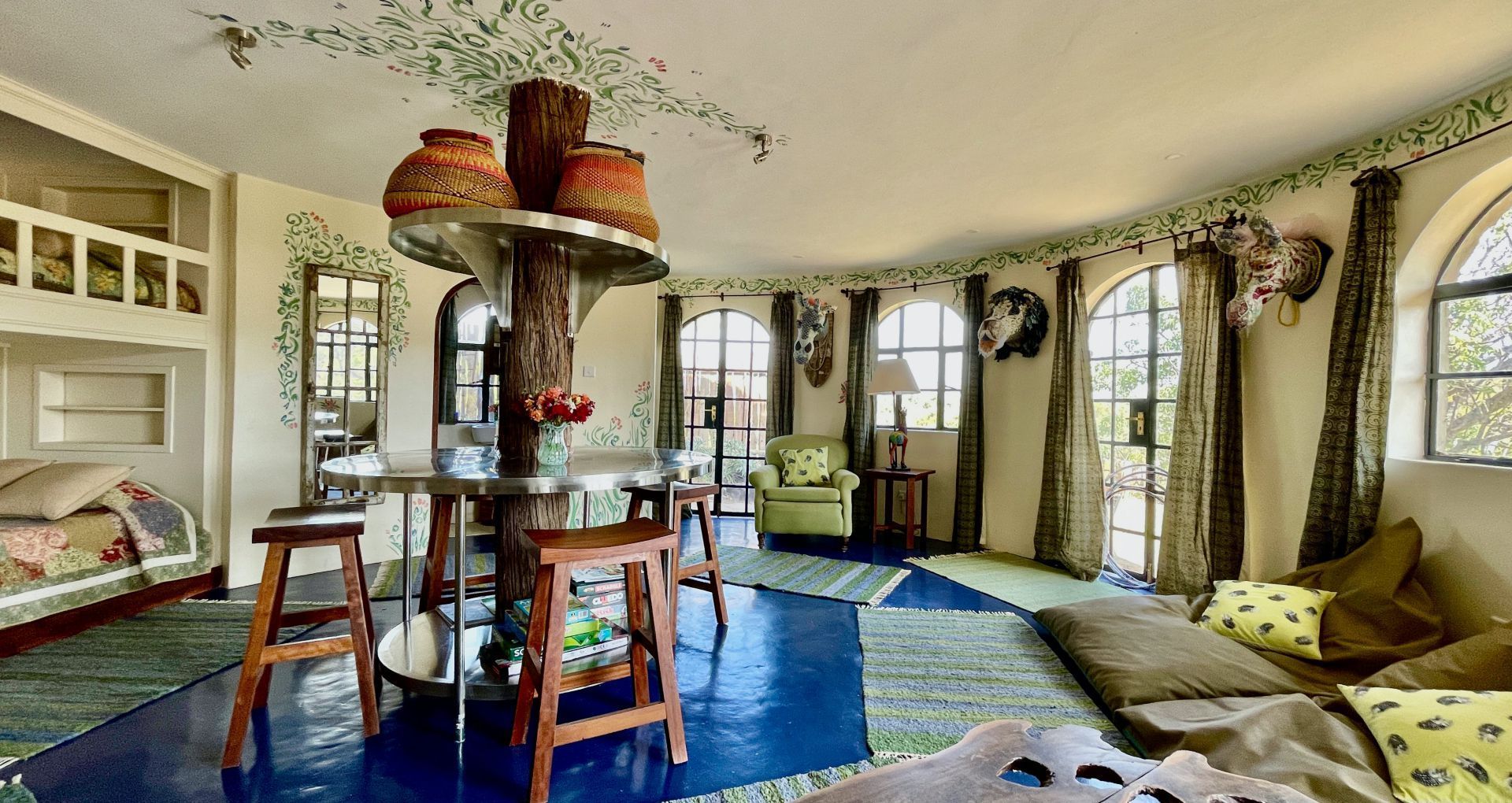 Cozy living room with arched windows, blue rug, sectional sofa, and central wooden shelf around a fireplace.