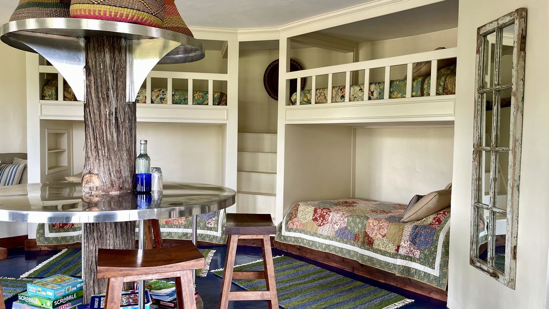 Cozy living room with built-in benches, patterned cushions, a round table, and a tree-trunk post under a lantern shade