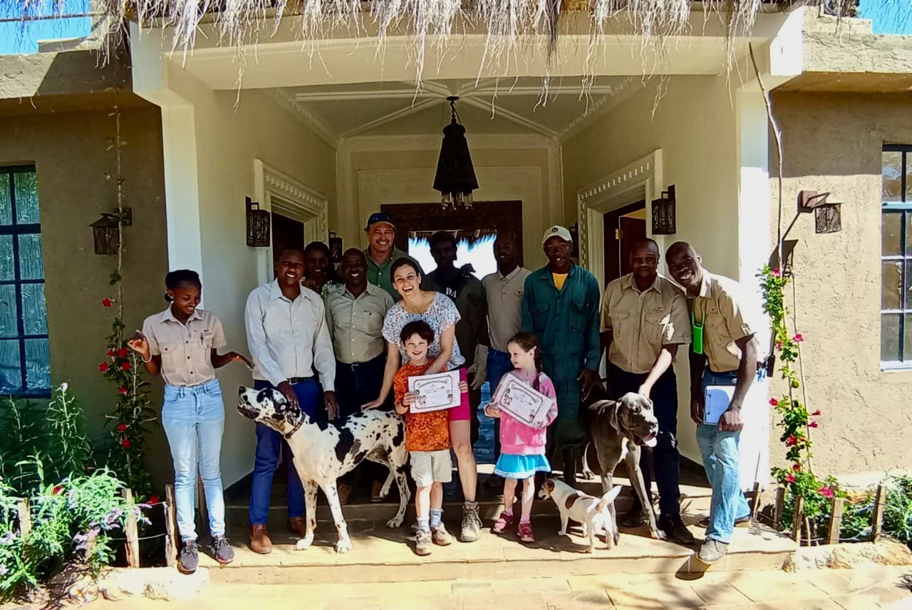 Group posing with goats under a porch decorated with hanging streamers.