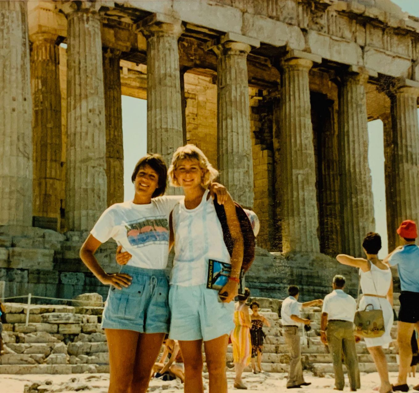 Two tourists posing in front of ancient stone columns and ruins outdoors