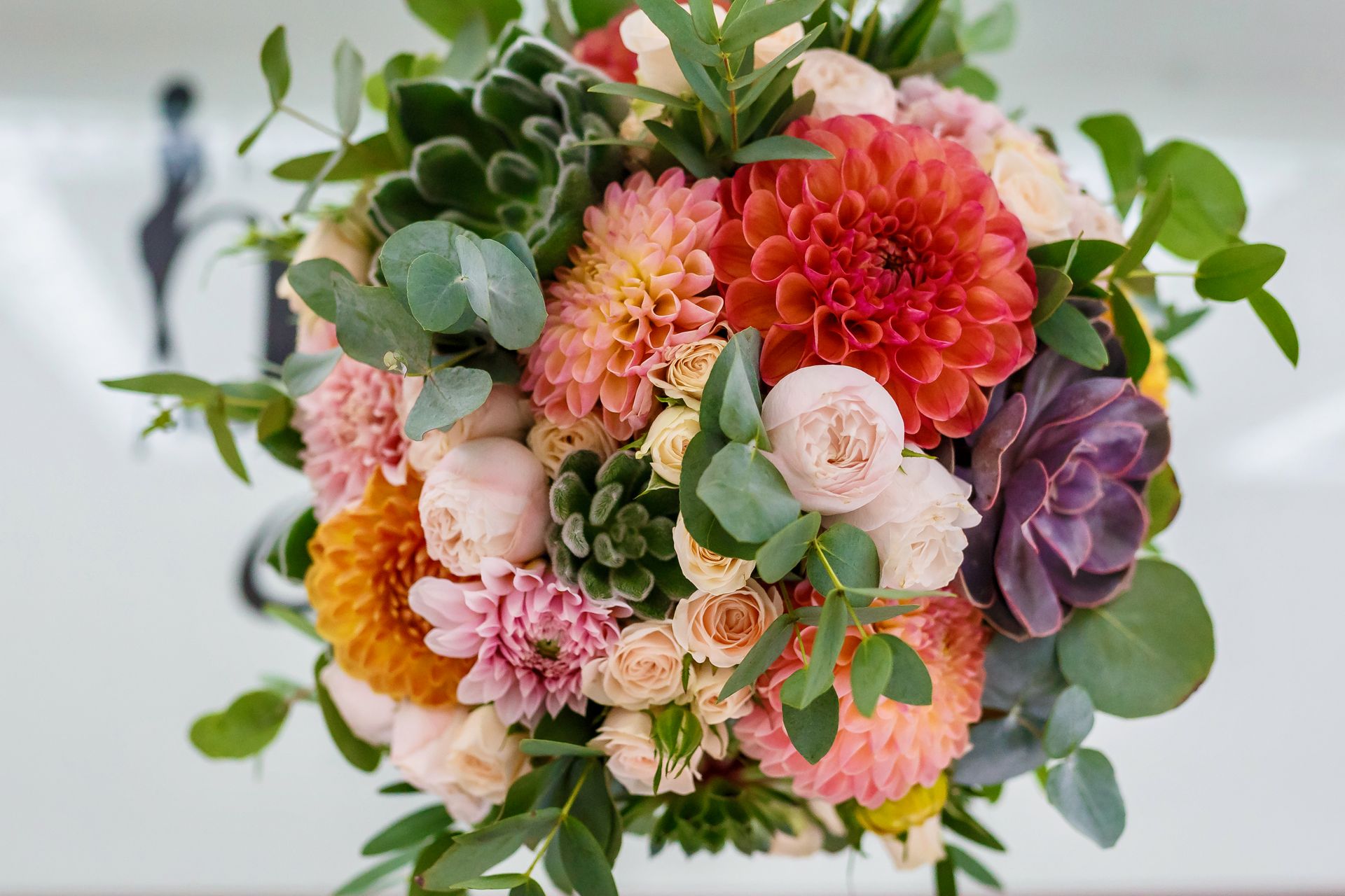 Colorful bouquet of dahlias and roses in pink, peach, coral, and purple with green foliage