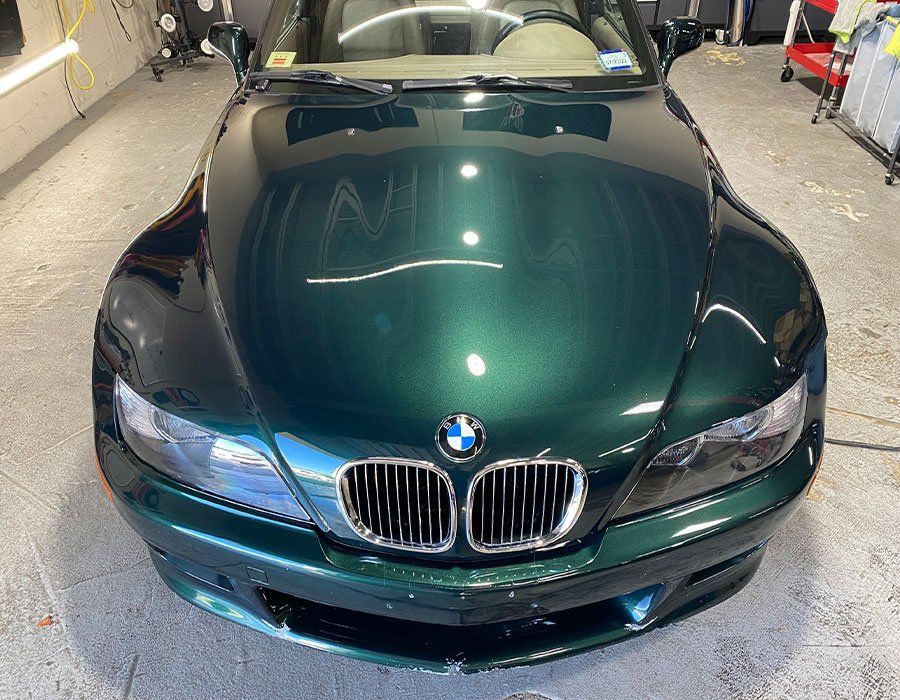 A green bmw z3 is parked in a garage