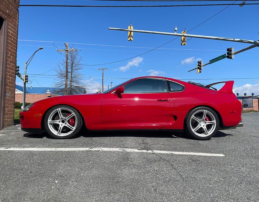 A red toyota supra is parked in a parking lot.