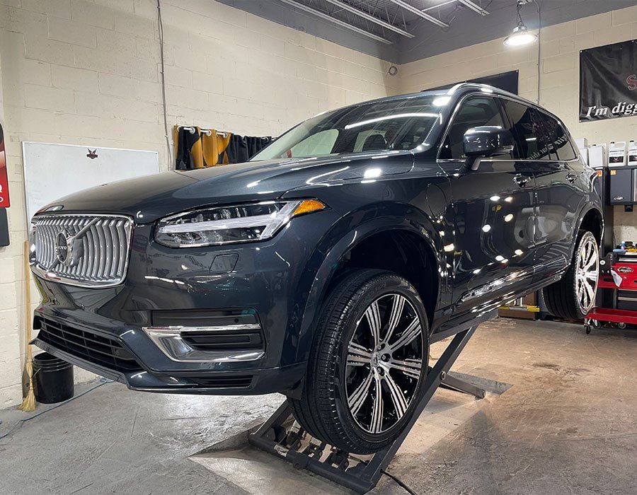 A volvo xc90 is sitting on a lift in a garage.