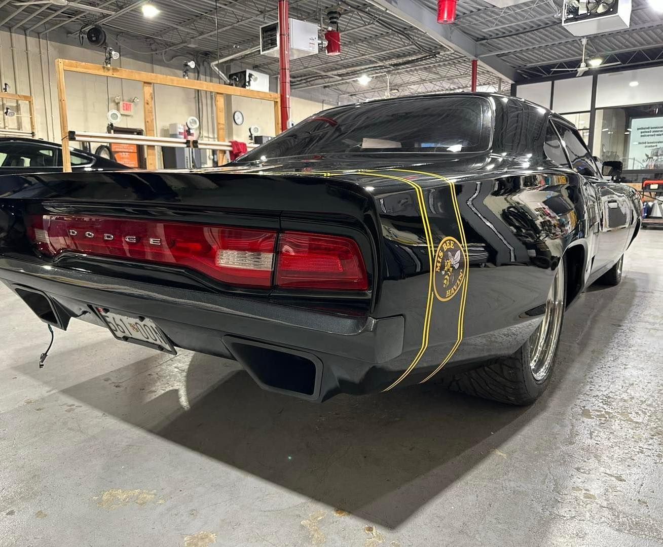 A black dodge charger is parked in a garage.