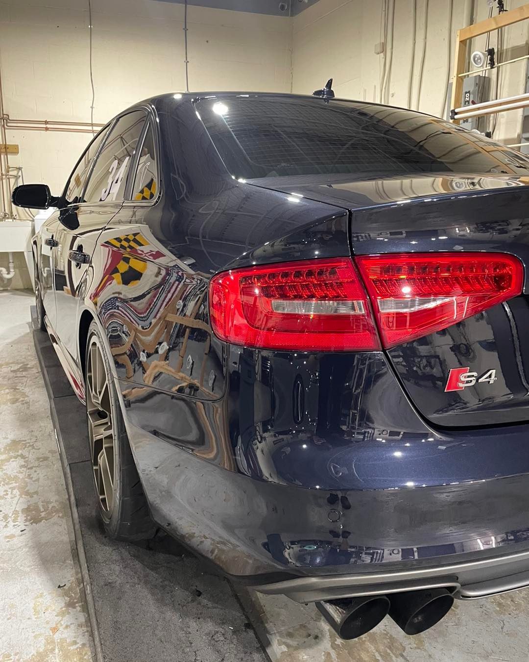 A black car with red tail lights is parked in a garage.
