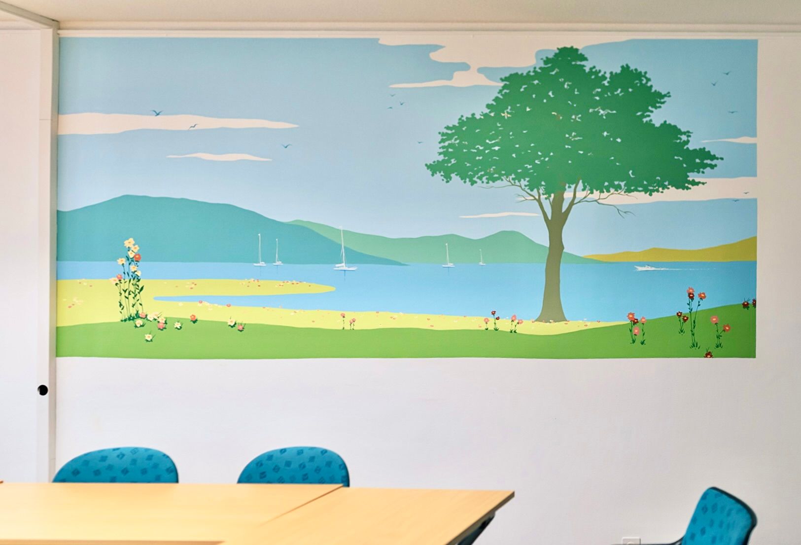 Conference room wall mural of a lakeside landscape with a large tree, sailboat, and small flowers