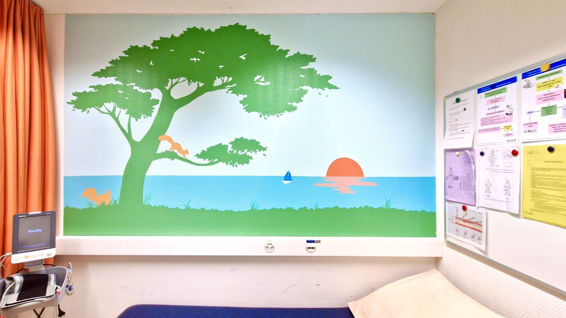 Mural of a green tree by a calm blue sea with a setting sun, in a classroom or office corner