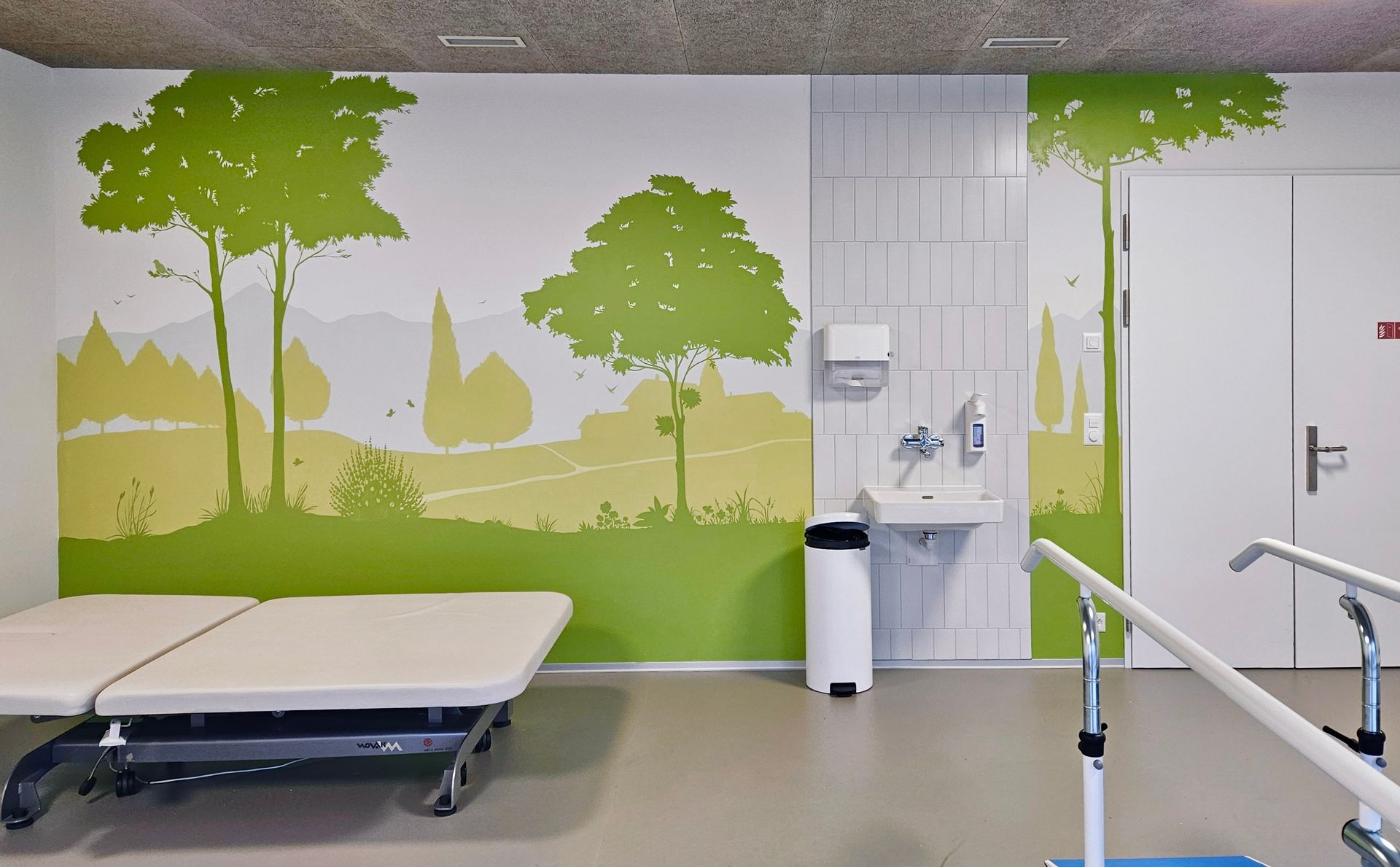 Accessible hospital room with mural, bed, sink, and wheelchair ramp