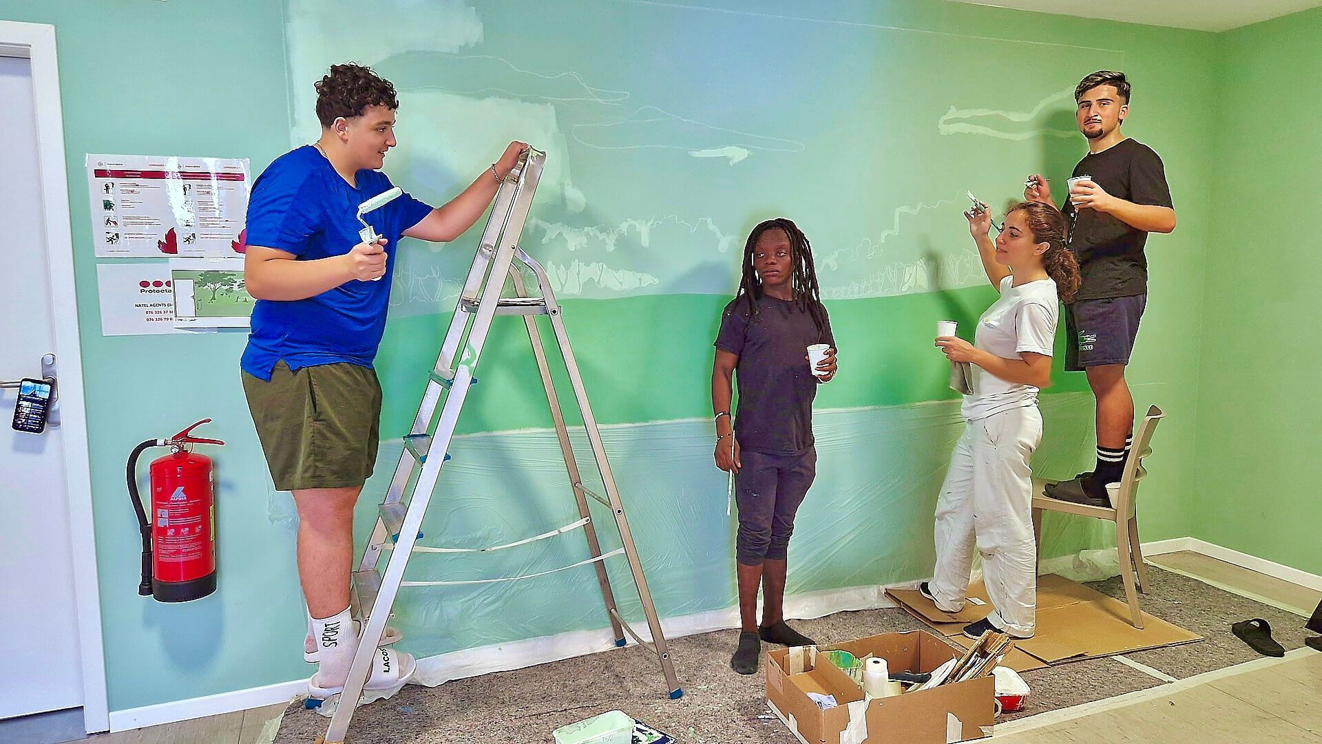 People painting a room green, using ladders and rollers during a renovation.