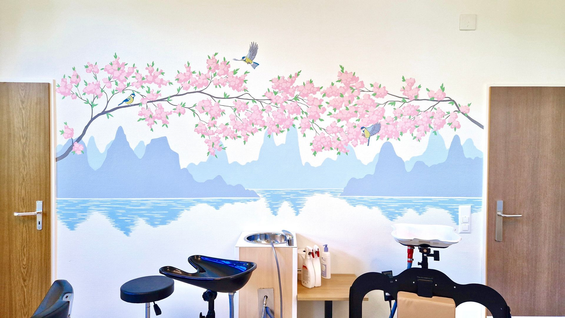 Fitness room with cherry blossom mural, exercise bikes, and a small table beneath a blue mountain scene