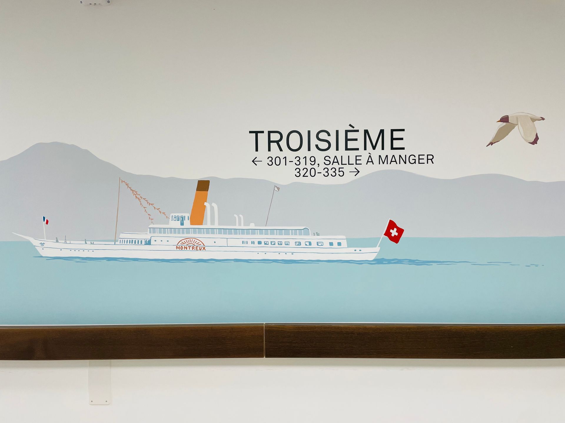 Illustrated ferry on calm sea with “TROISIÈME” text and distant island backdrop
