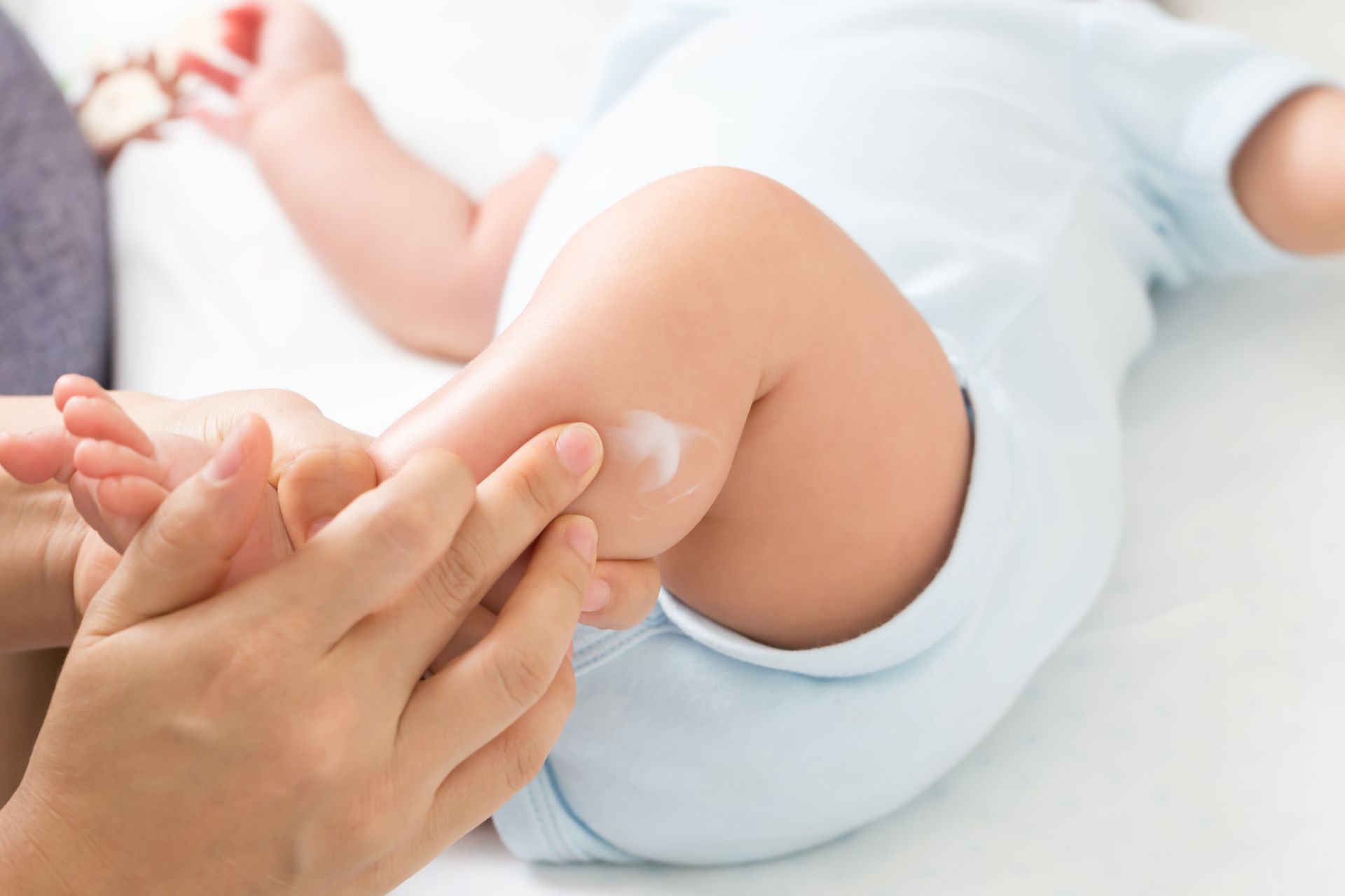 A woman is applying lotion to a baby 's leg.