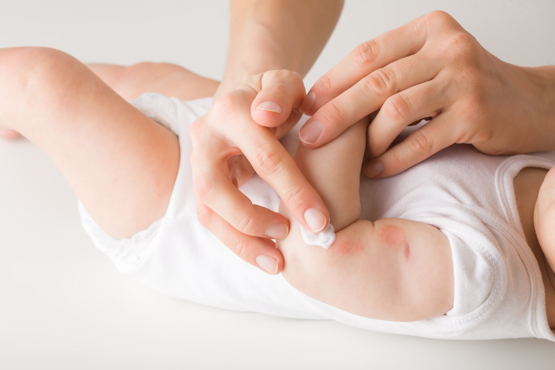 A woman is applying lotion to a baby 's arm.