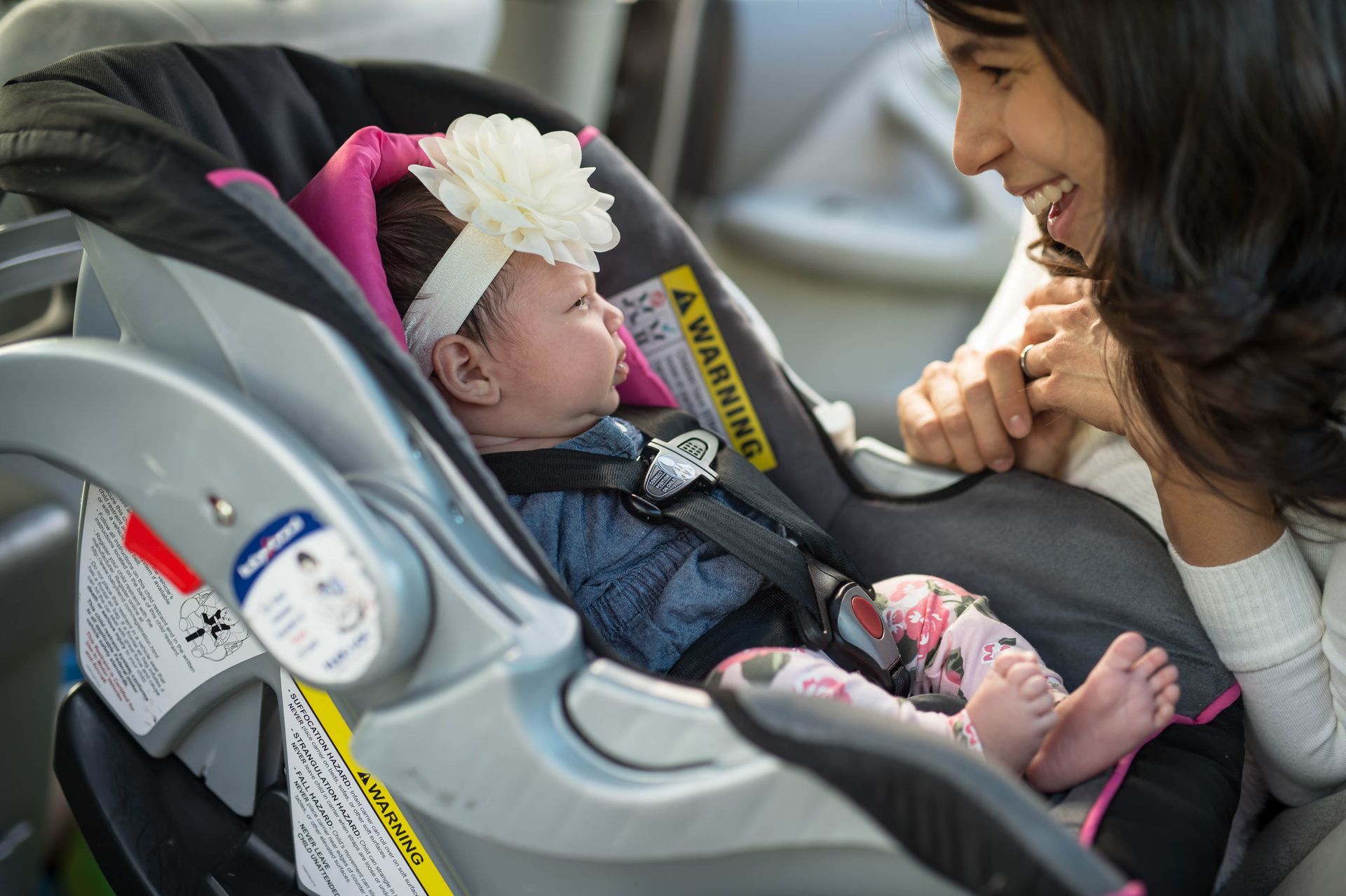 A woman is holding a baby in a car seat.