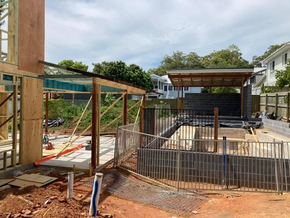 A Construction Site with A Fence and A House in The Background — Polson Construction in Kedron, QLD