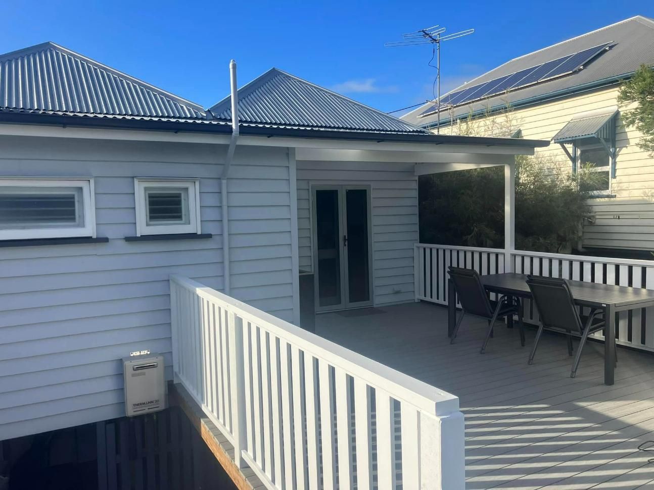 A White House with A Balcony with A Table and Chairs on It — Polson Construction in Kedron, QLD