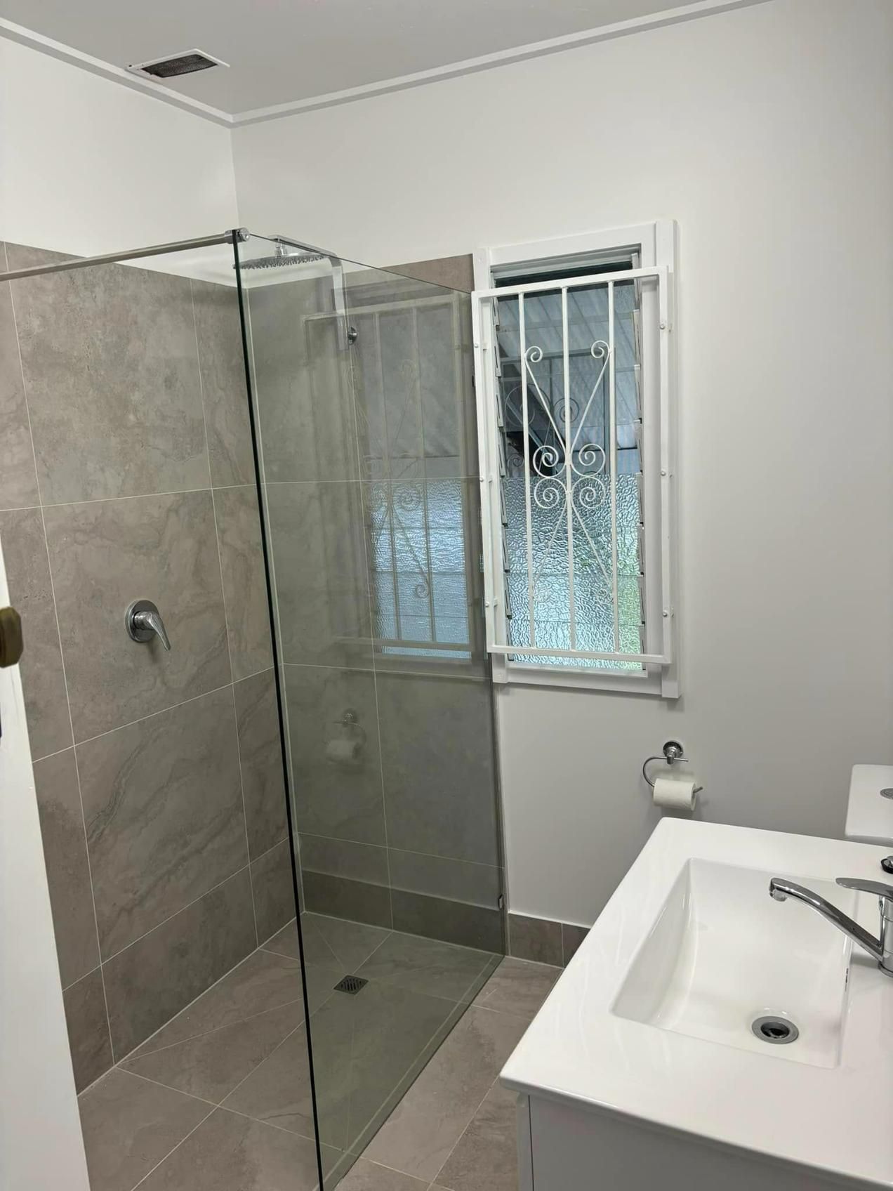 A Bathroom with A Walk in Shower, Sink, and Window — Polson Construction in Kedron, QLD