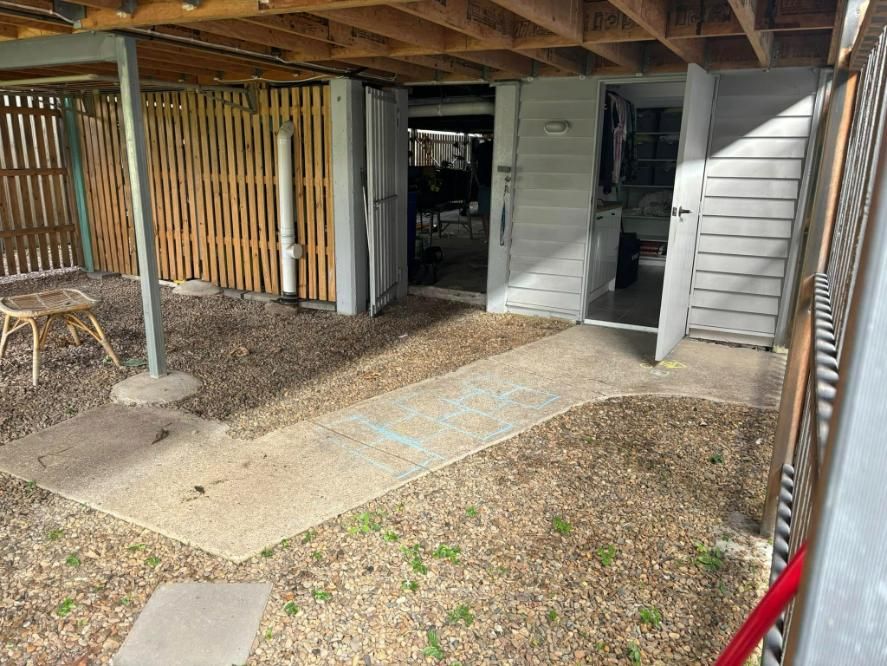 A Patio with A Wooden Fence and A Concrete Walkway Leading to A House — Polson Construction in Kedron, QLD