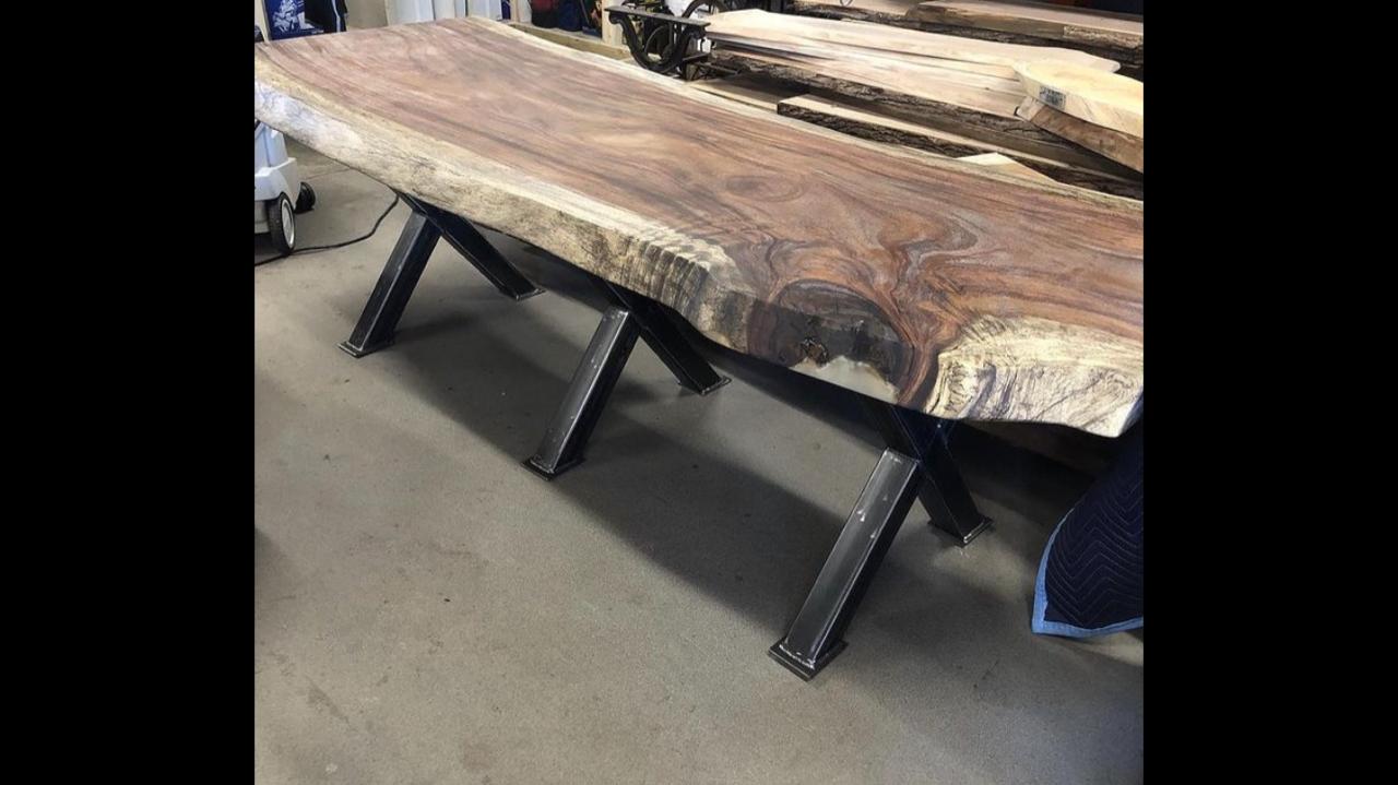 A wooden table with metal legs is sitting on a concrete floor.