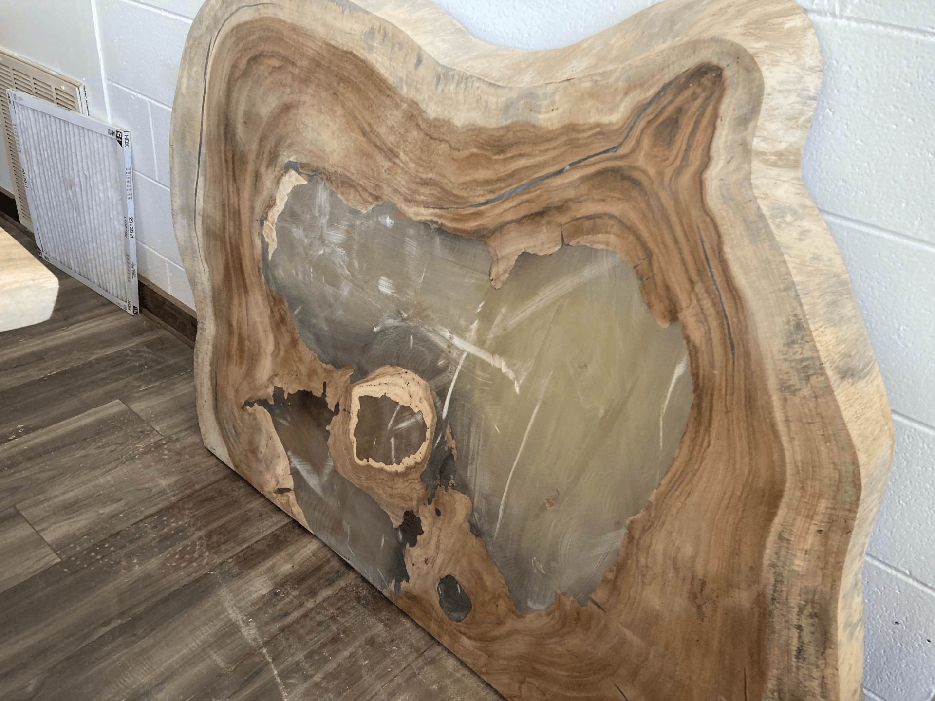 A large piece of wood is sitting on a wooden floor.