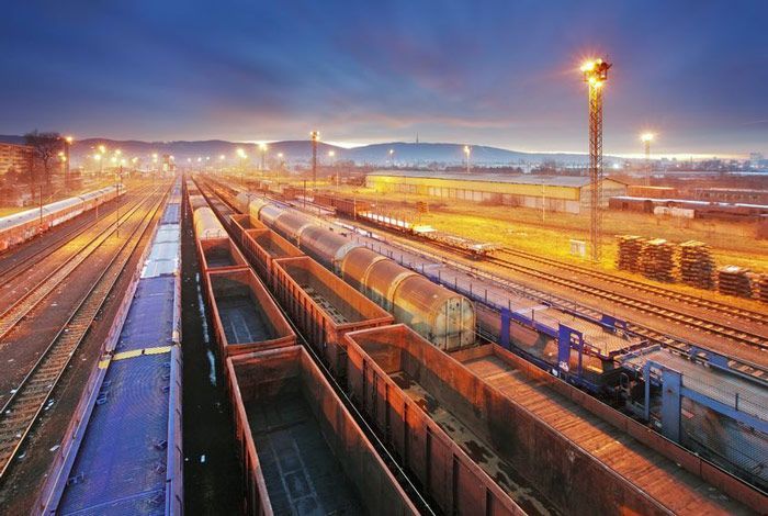 A train yard at night with a lot of train cars on the tracks.