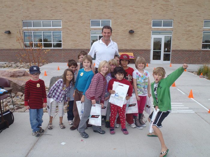 A group of children are posing for a picture with a man in front of a brick building